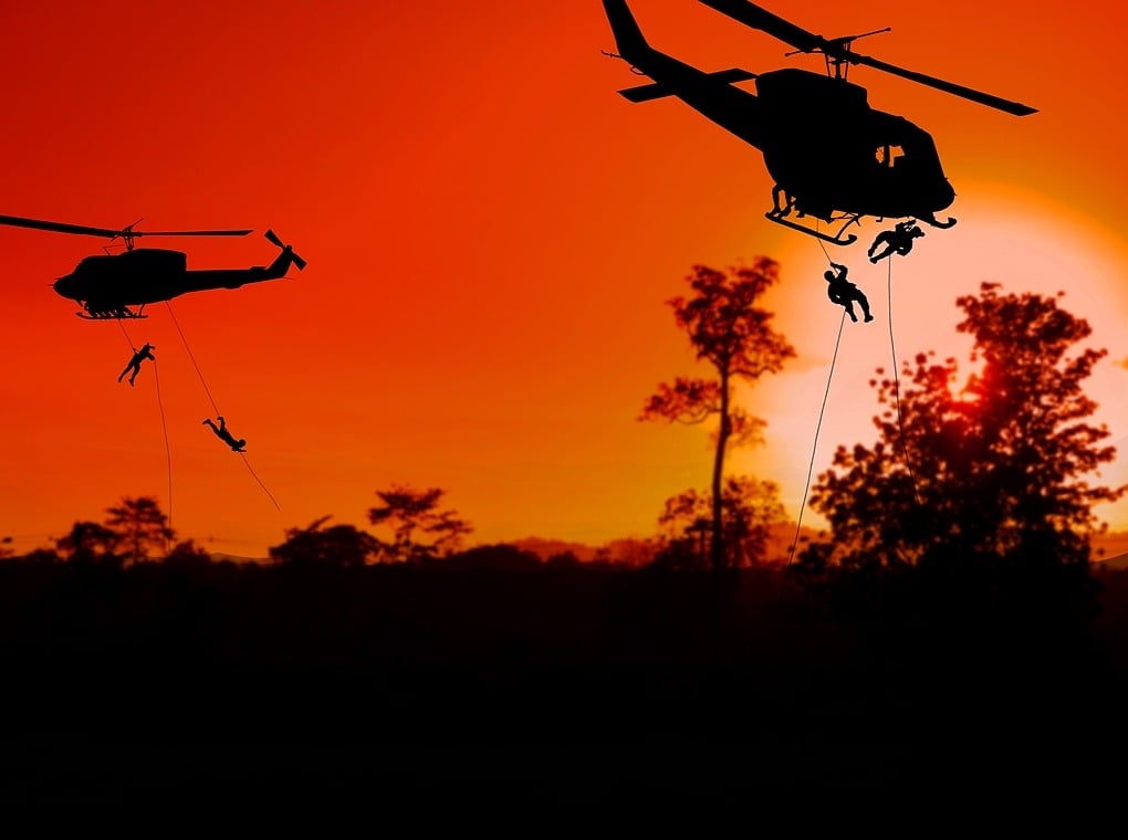 soldiers descending from helicopters at sundown